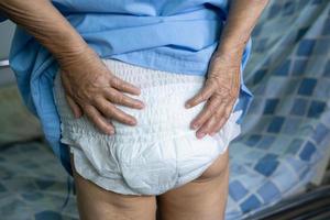 Paciente asiático mayor o mayor de la mujer de la señora mayor que lleva el pañal de la incontinencia en la sala del hospital de enfermería, concepto médico fuerte sano. foto