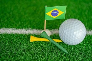 Golf ball with Brazil flag and tee on green lawn or grass is most popular sport in the world. photo
