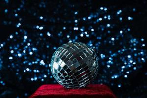 bola de discoteca en el podio de terciopelo rojo sobre fondo de lentejuelas azules foto