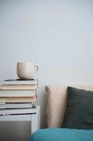 taza de café taza de té en una pila de libros al lado de una cama