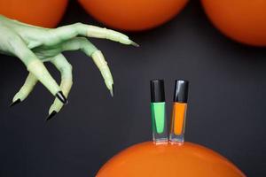 mano de bruja verde y esmalte de uñas verde y naranja con globos foto