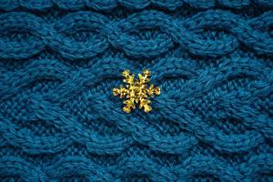 teal blue knit sweater background with yellow snowflake photo