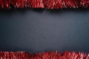 red tinsel frame on black paper background photo