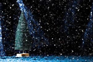 mini Christmas tree on sequin and knit background with snow photo