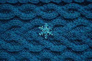 teal blue knit sweater background with blue snowflake photo