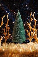 mini Christmas tree on sequin background with tinsel and trees photo