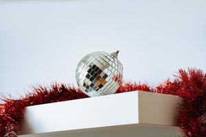 Disco ball and red tinsel on white background photo