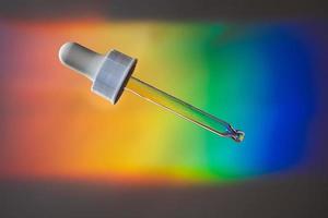 Levitating Glass dropper on a prism rainbow background photo