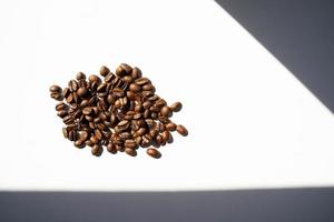 Isolated roasted coffee beans in harsh light photo