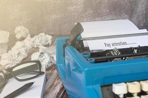 texto escrito en una vieja máquina de escribir azul y papel de basura en un escritorio de madera. foto