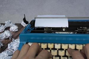 hombre de negocios manos escribiendo en una vieja máquina de escribir y fondo de papel de basura. foto