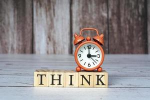 Think text on wooden blocks and alarm clock set at 3 o'clock on table. photo