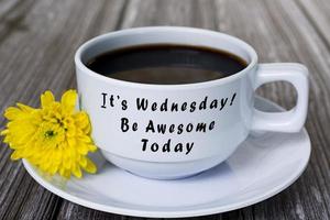 Text on white coffee cup with yellow flower on wooden desk. Wednesday concept. photo