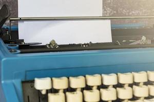 An old blue typewriter and trash paper on wooden desk. Copy space photo