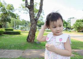 Niña asiática de 3 años rascándose la cabeza. foto