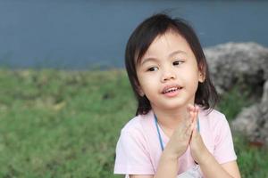 Positive charming 4 years old cute baby Asian girl, little preschooler child smiling and looking to the left photo