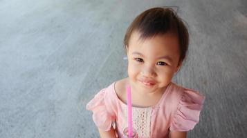 Niña asiática de 3 años sonriendo felizmente al aire libre, Tailandia. foto