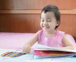 Headshot of smiling 2-3 years old cute baby Asian girl, little toddler child choosing colourful pencils. photo