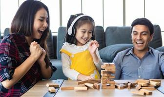 familia de raza mixta, hija y padre caucásico y madre asiática, jugando al juego de madera juntos con fondos y emocionados. foto