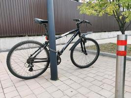 Bicycle strapped to a street pole. Sport. Bicycle ride. Travel. Transport. photo