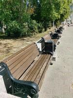 Empty wooden benches with beautiful metal legs stand in the park on a summer day. Place of rest and relaxation. photo