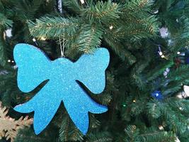 Blue decorative bow, on the green branches of a spruce. Decoration on the Christmas tree. Festive background. Close-up. photo