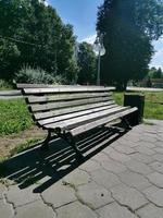 banco de madera vacío de pie con patas de metal en verano en un parque de la ciudad. lugar de descanso. foto