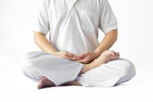 A man in a white robe meditating against a white backdrop with a clipping path. photo