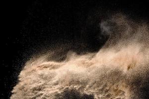 Dry river sand explosion. Golden colored sand splash agianst dark background. photo