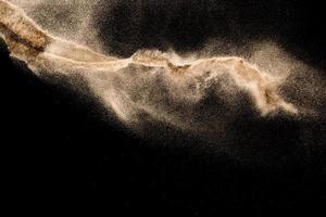 Dry river sand explosion. Golden colored sand splash agianst dark background. photo