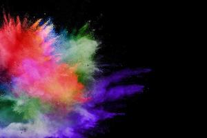 Abstract multicolored powder explosion on black background. Color dust particle splattered on background. photo