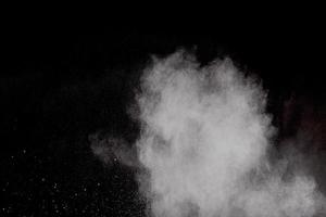 extrañas formas de nube de explosión de polvo blanco sobre fondo negro.salpicaduras de partículas de polvo blanco. foto