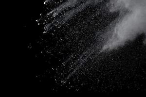 White powder explosion isolated on black background.White dust particle splash. photo