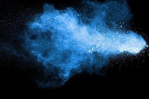 Blue purple dust explosion on black background. Freeze motion of color powder splashing. photo