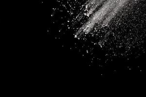 White powder explosion isolated on black background.White dust particle splash. photo
