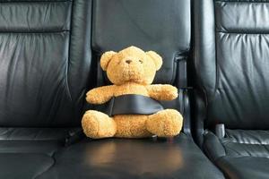 Teddy bear fastened in the back seat of a car photo