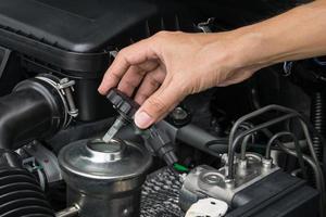 A mechanic is opening the oil cap from a car engine. photo