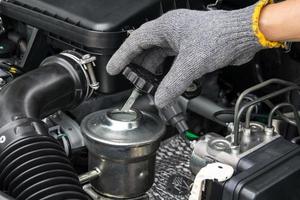 Un mecánico está abriendo el tapón de aceite del motor de un automóvil. foto