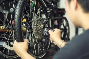 mecánico de bicicletas repara bicicletas plegables en taller. ajustar el desviador trasero, el concepto de mantenimiento y reparación foto