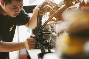 mecánico de bicicletas repara bicicletas plegables en taller. ajustar el desviador trasero, el concepto de mantenimiento y reparación