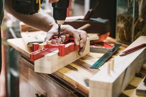 carpenter use drill bit and centering dowel jig tool to make strong joints . woodworking concept.selective focus photo