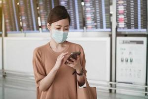 women is wearing medical face masks to protect themselves from pollution  germs and coronavirus  and using smartphone device to send a text message at the airport. photo