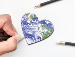 hand writing a heart-shaped globe representing love  Elements of this image furnished by NASA. photo