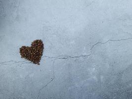 Love or Valentine concept. Closed up coffee beans in heart shape on isolated grey wallpaper background photo