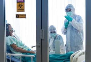 Doctors in protective suit vaccinate and monitor blood pressure the patient infected with CORONA VISRUS or COVID-19 in quarantine room at the hospital. photo