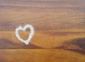Love or Valentine concept. Closed up salt in heart shape on isolated wooden surface background photo