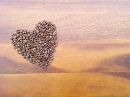 Love or Valentine concept. Closed up coffee beans and flowers in heart shape on isolated grey wallpaper background photo