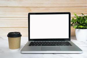 Laptop or notebook with blank screen, coffee and potted plant on white table. photo