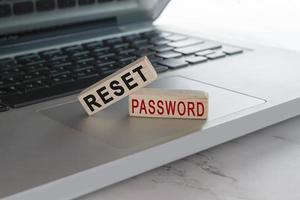 Reset password text on wooden block cube placed on laptop or notebook. photo