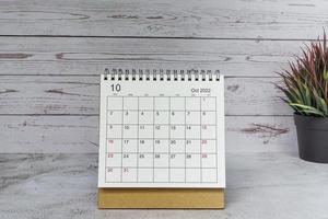 Calendario blanco de octubre de 2022 con planta en maceta sobre escritorio de madera. concepto de año nuevo 2022 foto